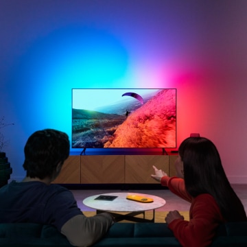 一對夫婦正在欣賞電視的 LED 燈，其色彩與螢幕同步。